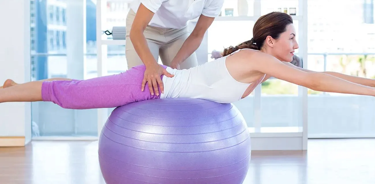 A therapist guiding a patient through a stability-ball exercise